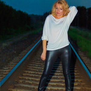 Mergina pozuojanti ant geležinkelio bėgių