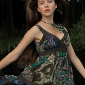 Mergina palaidais ilgais plaukais, raštuota suknele. A girl with loose long hair in a patterned dress.
