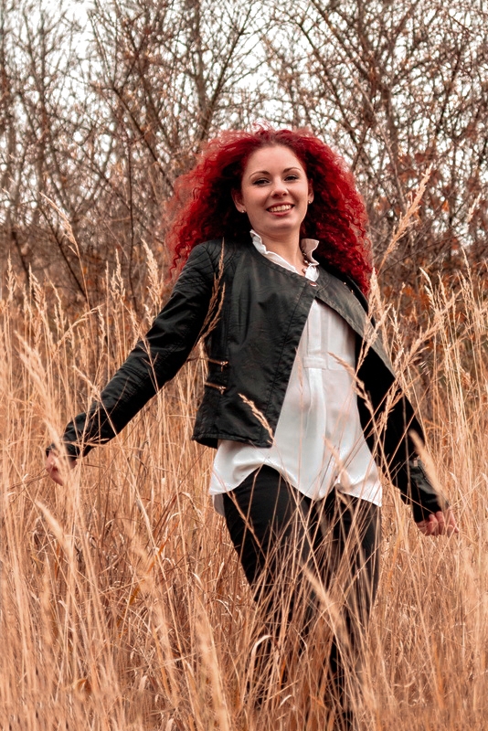 Kadras iš fotosesijos: mergina raudonais ilgais plaukais javų lauke. A shot from a photo shoot: a girl with long red hair in a cornfield.